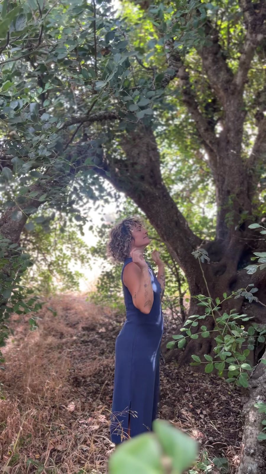 Noemí Soto bajo un árbol, con los ojos cerrados